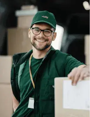 smiling ridly employee in front of loaded truck